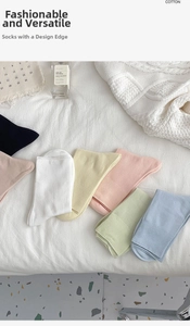 Stack of colorful pastel cotton crew socks in ribbed knit texture on white bedding