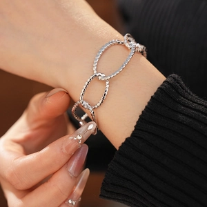 Close-up of a chunky silver irregular oval hollow chain bracelet worn on a female wrist