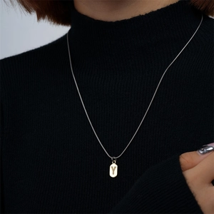 Collana con ciondolo lettera Y dorata e zirconi indossata da una modella su maglia nera