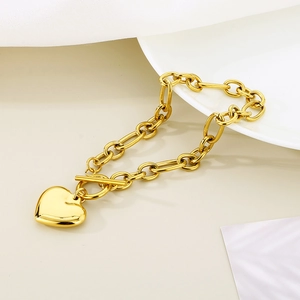 Detailed view of a gold heart pendant bracelet with a stylish toggle clasp on a white surface