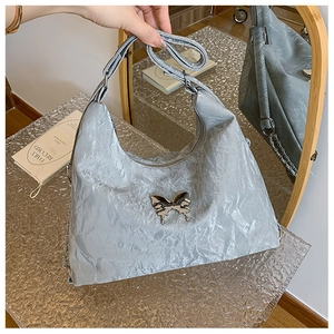 Detail view of a grey pleated shoulder bag with a silver metallic bow decoration