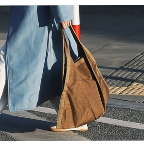 Street style view of a brown pleated tote bag paired with a blue winter coat
