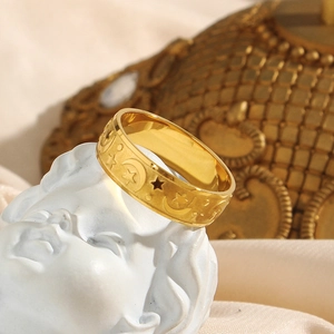 Golden wide ring with moon and star relief displayed on an angel statue head