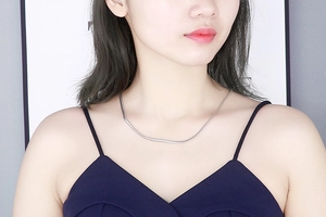 Gros plan d'un collier chaîne serpent argentée porté par un mannequin sur fond blanc