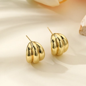 Detail view of gold-plated geometric ribbed earrings with glossy metallic texture