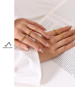Detail showing a set of four golden stainless steel chain rings worn on a hand