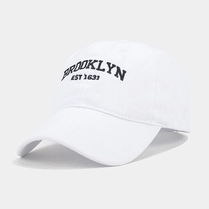 Close-up of embroidered Brooklyn text on white washed cotton baseball cap with ventilation holes