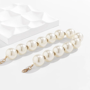 Macro detail of faux pearl necklace with rhinestone rings on white geometric props
