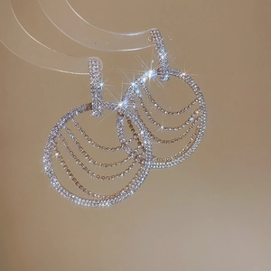 Gros plan sur des boucles d'oreilles argentées avec cercles superposés et pavé de cristaux