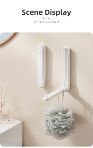 Wall-mounted folding hook made of white plastic shown in a home bathroom setting