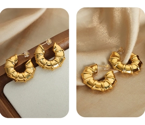 Macro detail of golden croissant earrings with textured bamboo geometry and high-shine finish