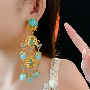 Detailed close-up of vintage gold hollow flower earrings with green and blue crystals