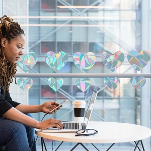 Holographic heart window stickers creating rainbow prism effects in a home office setting