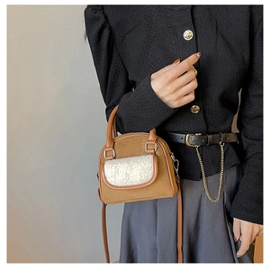 Detail of plush lamb wool pocket on brown suede handbag with metal strap hardware