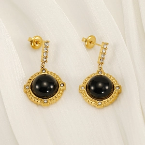 Detail of gold-plated earrings featuring black stone centers and small white zircons
