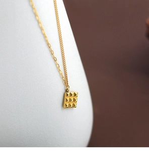 Detailed view of the gold-plated chocolate grid pendant and asymmetric titanium steel chain