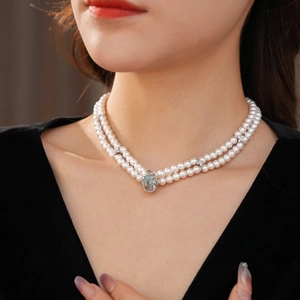 Détail d'un collier de perles double épaisseur avec un grand pendentif en pierre bleue claire