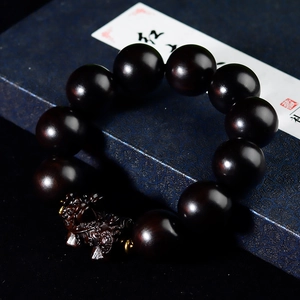 Dettaglio del bracciale con perle di legno scuro e ciondolo Pixiu inciso a mano