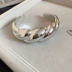 Macro view of twisted silver bangle with high-polished metallic texture in a jewelry box