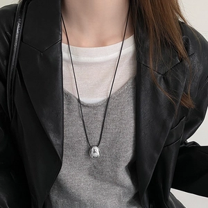 Minimalist wax cord necklace with a polished oval silver pendant on female model