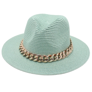 Texture détaillée d'un chapeau fedora vert menthe orné d'une grosse chaîne dorée