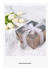 Close-up of geometric pattern gift wrap with white lace ribbon bow on a cozy knit surface