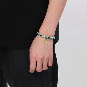 Détail d'un bracelet de perles turquoise et noires avec un pendentif croix dorée