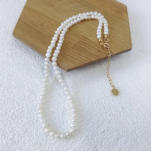 Close-up of natural freshwater pearl necklace with gold clasp on wooden display tray