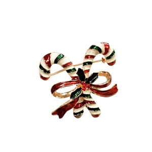 Detailed view of enamel Christmas candy cane brooch with bow and holly accents