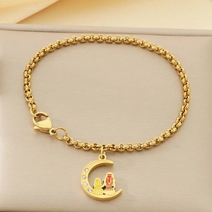 Détail d'un bracelet doré avec pendentif lune, figurines gravées et petits diamants