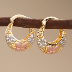 Elegante gouden oorringen met zilveren bloemendetails en roze vlinderhangers aan takken