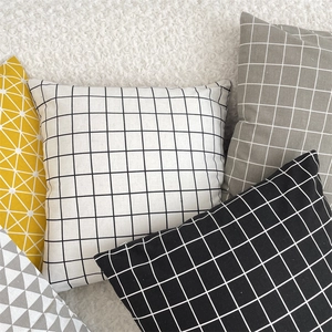 Close-up of geometric cotton linen pillowcases with grid and triangle patterns on white rug