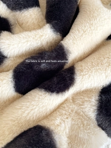 Close-up of soft black and white cow print plush faux fur fabric texture on tote bag