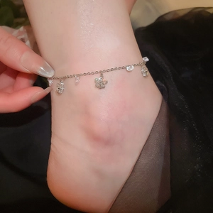 Détail d'une chevillère en argent avec pendentifs fleurs en zircone sur la cheville