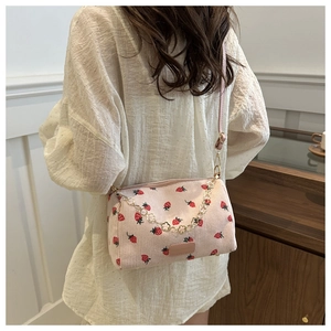 Pink corduroy crossbody bag with strawberry print and gold heart chain on white shirt