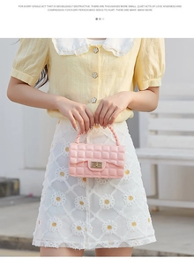 Pink quilted PVC jelly bag with metallic twist lock held by model in soft daylight