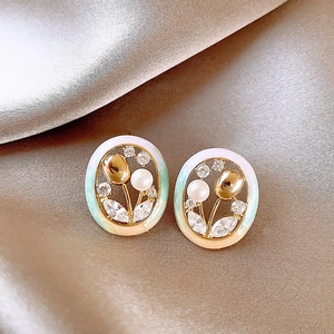 Macro shot of tulip enamel earrings with white pearls and sparkling zircons on silk