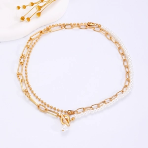 Detail of layered gold paperclip chain and white pearl necklace with baroque pendant