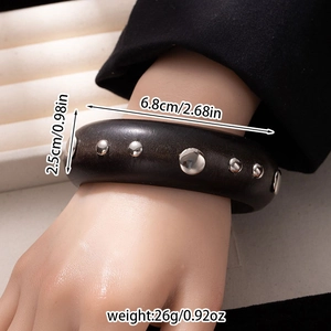 Detail showing wide black wood bangle with silver metal studs and size dimensions
