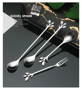 Detailed view of stainless steel leaf spoons and fruit fork set on marble tray