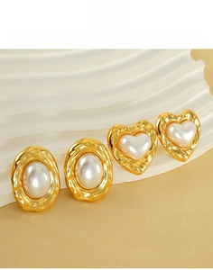 Detail of vintage gold titanium steel earrings with heart and oval pearl inlays