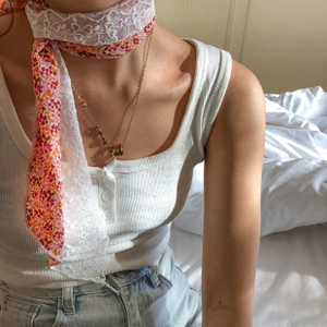 Detail of elegant floral silk scarf with white lace trim and gold ring pendant necklace