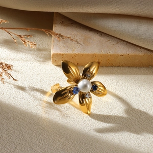 Macro shot of gold flower ring with center pearl and blue white diamond details