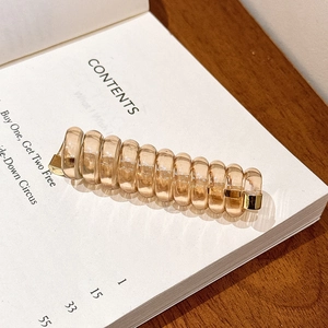 Détail d'un élastique spirale ambré avec touches dorées posé sur un livre ouvert