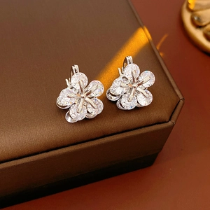 Vue macro de boucles d'oreilles fleur en argent et zircon sur une boîte à bijoux sombre