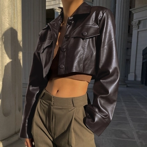 Gros plan sur la texture du cuir PU marron foncé et les boutons d'une veste courte motard
