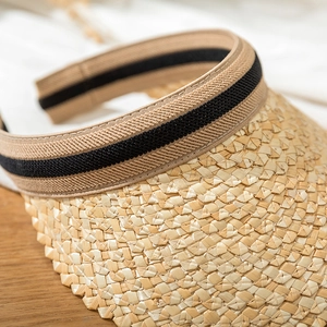 Macro view of woven straw sun hat texture with decorative dark brown striped ribbon
