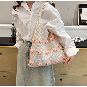 Detailed knit texture of beige crochet tote bag with 3D pink flowers and knitted pattern
