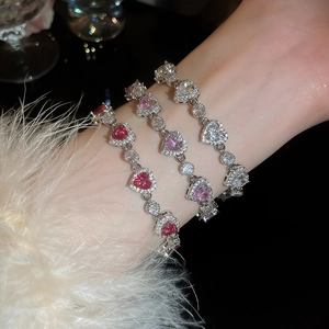 Close-up of three luxury heart zircon bracelets in red, pink, and white on a wrist