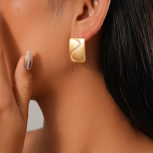 Detailed view of 18K gold plated rectangular earring with S-shaped zircon inlay on model